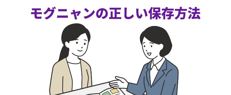 モグニャンの正しい保存方法」と紫色の見出しが上部にあり、白い机を挟んで向かい合う2人の女性を描いた線画イラスト。右側のスーツ姿の女性が、机の上の冊子を指し示しながら説明している。